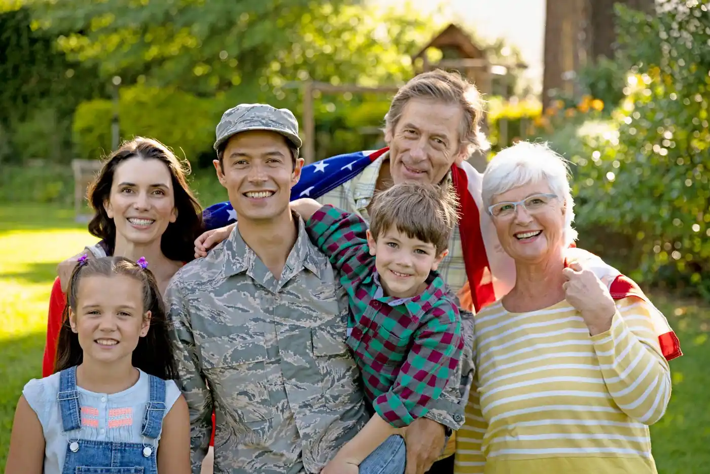 A service member in uniform smiling outdoors with his family